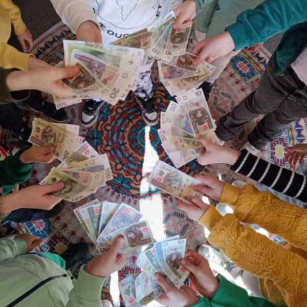 zdjęcie rączek dzieci trzymających zabawkowe banknoty o róznych nominałach