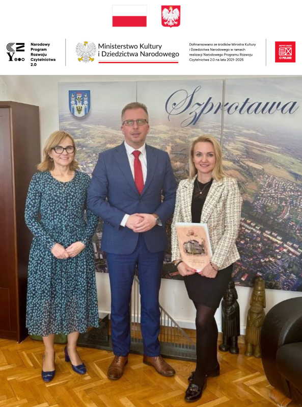 zdjęcie dyrektor biblioteki z burmistrzem i wiceburmistrzem na tle fototapety z napisem szprotawa na górze belka logotypowa i godło